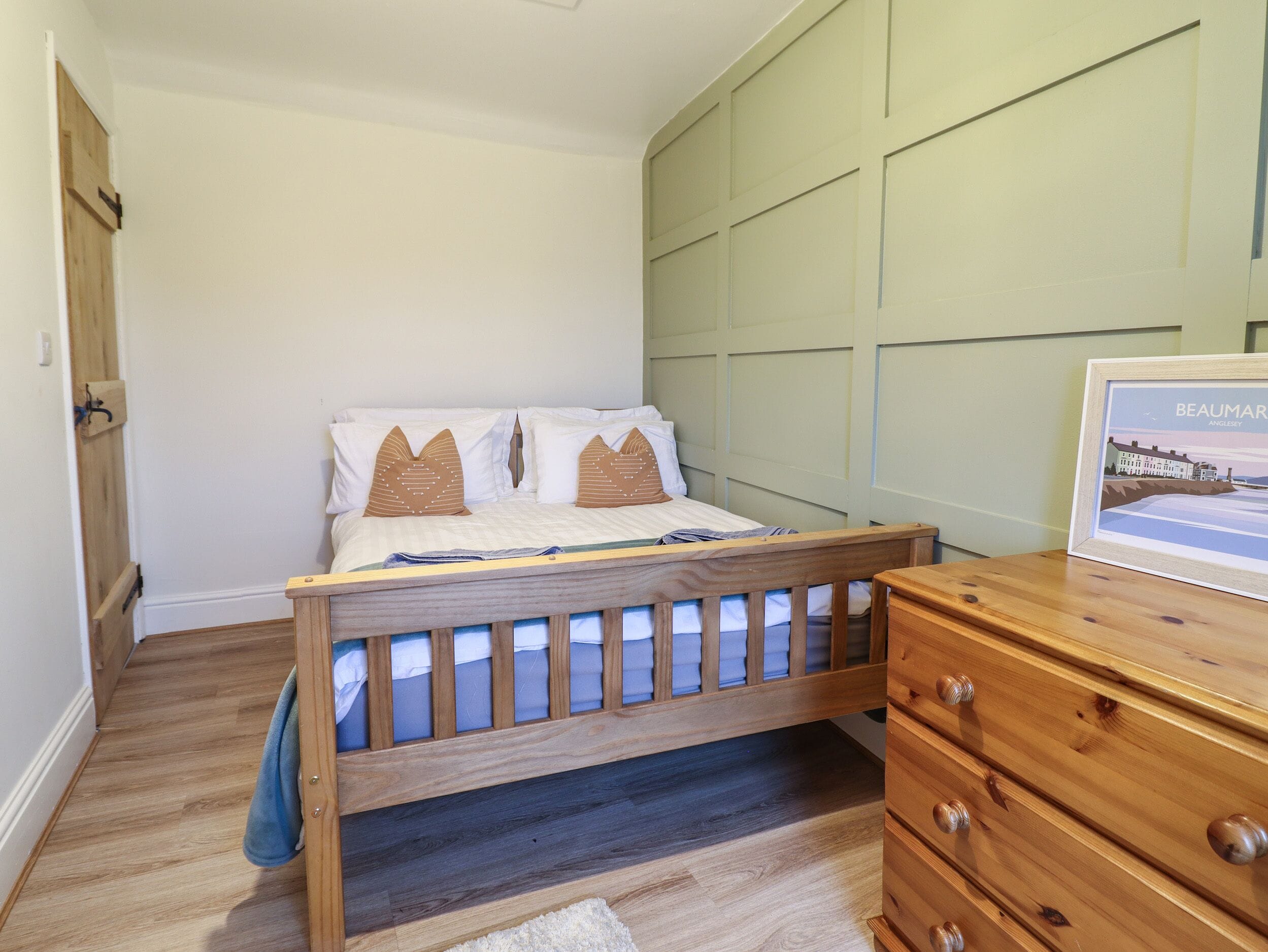 A bedroom with a wooden bed, a dresser, and a framed picture on the dresser.