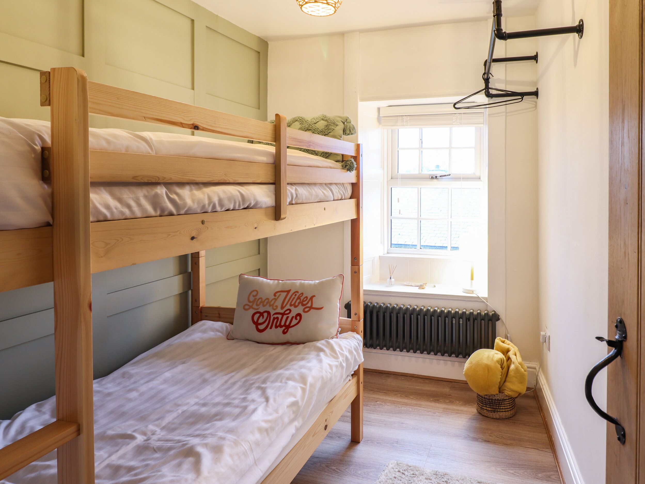 A bunk bed room with a window, radiator, and a yellow cushion.