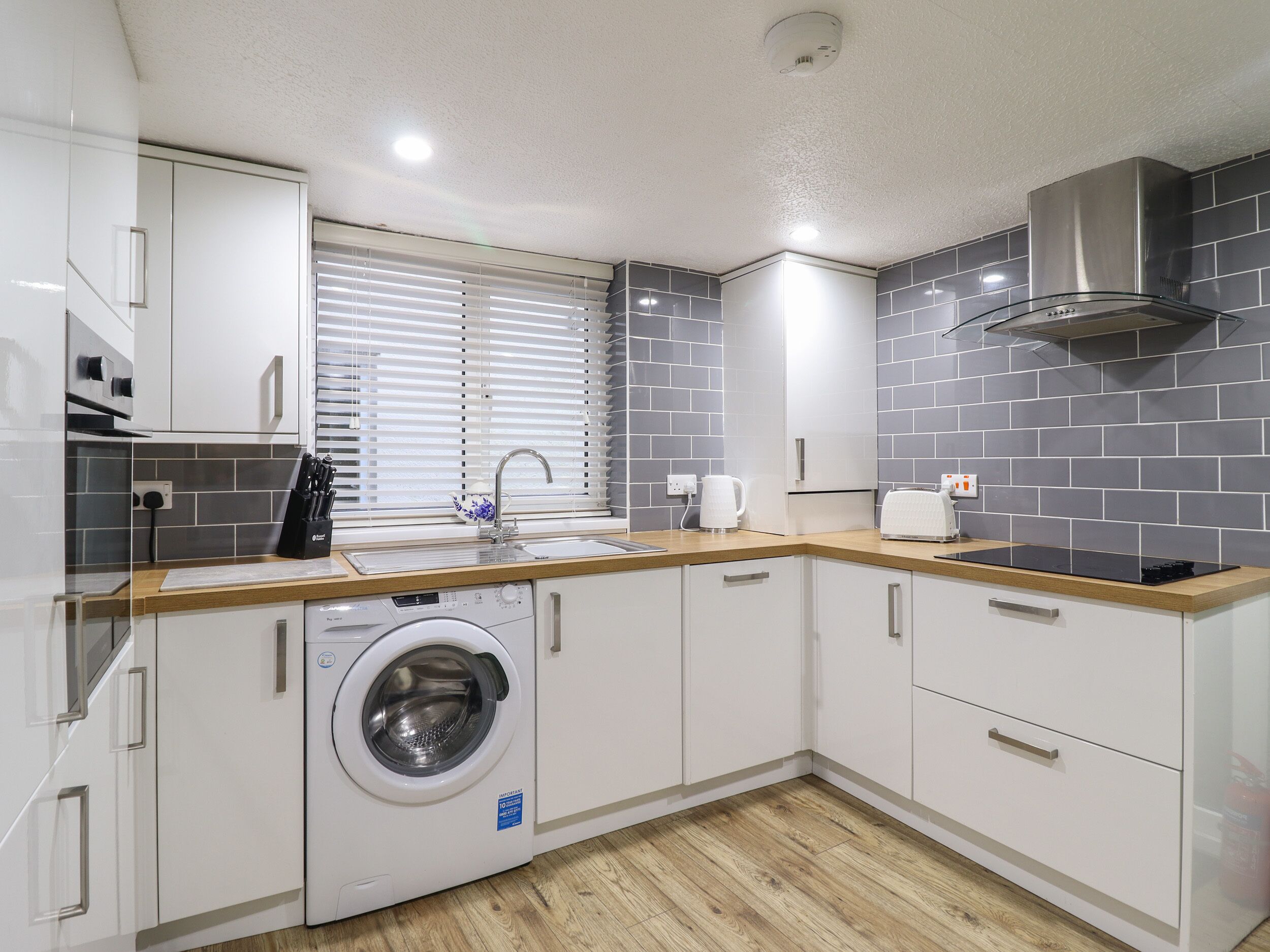 A modern kitchen with white cabinets, a built-in washing machine, a sink, and a stove.