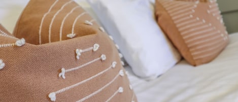 A bed with multiple pillows, some with white and others with brown covers.
