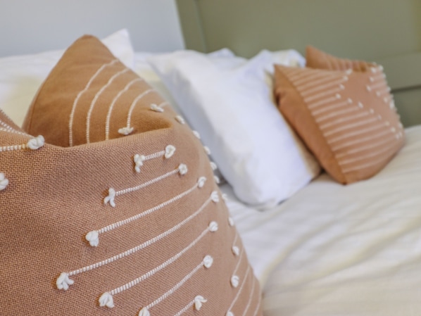 A bed with multiple pillows, some with white and others with brown covers.
