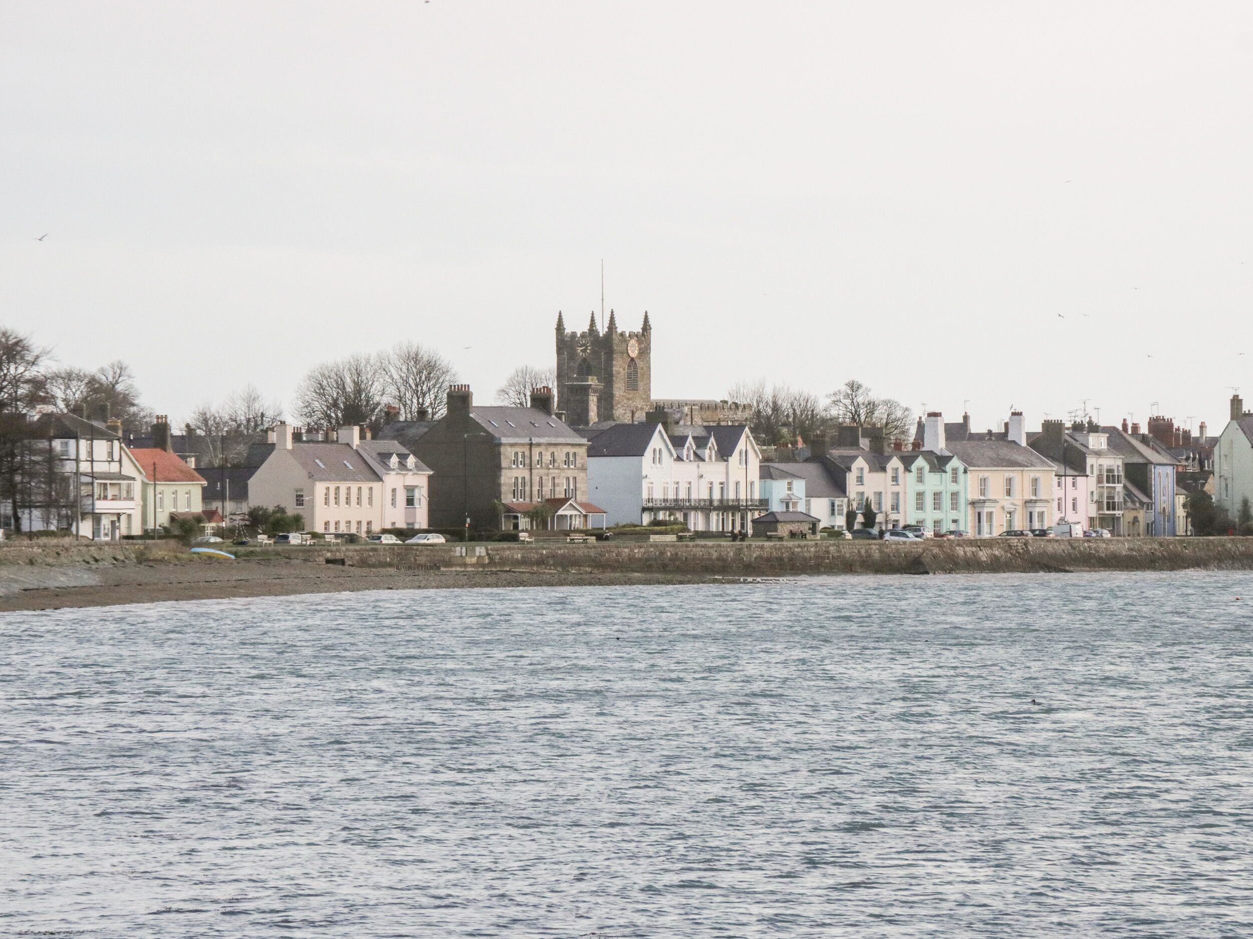 A coastal town with a prominent church tower and colorful houses along the waterfront.