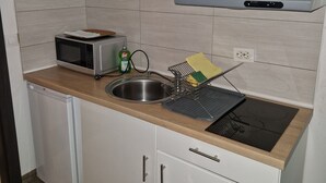 Eine kleine Küche mit Mikrowelle, Spüle und Geschirrtrockner.