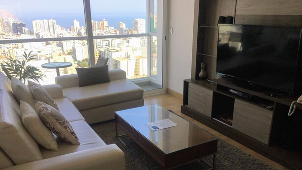 A modern living room with a sofa, a coffee table, and a TV. - Miraflores Upper Pardo Apartment 3bedroom/4baths (Miraflores)