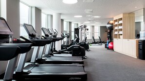 Une salle de sport équipée de plusieurs tapis de course, de vélos d’exercice et d’un grand ballon rouge pour faire de l’exercice.