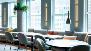 Un intérieur moderne comprenant un espace salon, des tables et de grandes fenêtres donnant sur la ville.