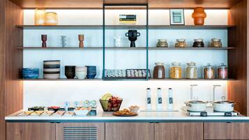 A kitchen with shelves holding jars, plates, and a buffet with labeled dishes.