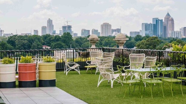 Terraço no telhado com área de estar ao ar livre, plantas em vasos e vista para o horizonte da cidade.