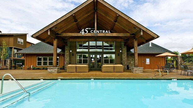 A building with a sign reading "45 CENTRAL" above the entrance, a pool in the foreground, and outdoor seating areas. - Exceptional Location & Vibes, New Décor, Artwork, & Furnishing, Community Pool, 8 Miles to Portland (Beaverton)