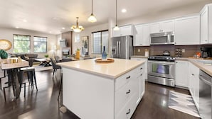 A modern kitchen with white cabinets, stainless steel appliances, and a large island. - Exceptional Location & Vibes, New Décor, Artwork, & Furnishing, Community Pool, 8 Miles to Portland (Beaverton)
