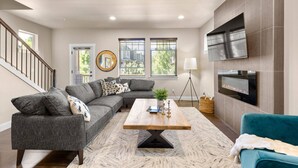 A modern living room with a sectional sofa, a coffee table, a TV, and a fireplace. - Exceptional Location & Vibes, New Décor, Artwork, & Furnishing, Community Pool, 8 Miles to Portland (Beaverton)