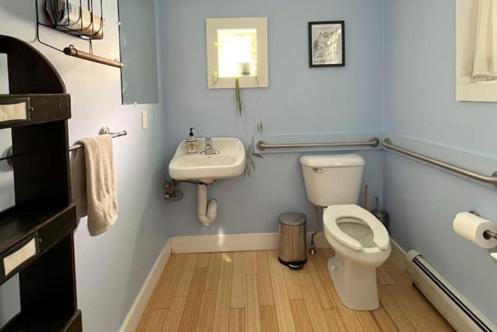 A small bathroom with a sink, toilet, and handrail.