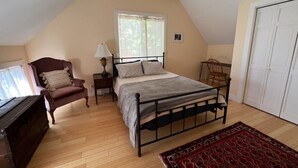 Une chambre à coucher avec un lit, une chaise, une lampe, une commode et une porte.