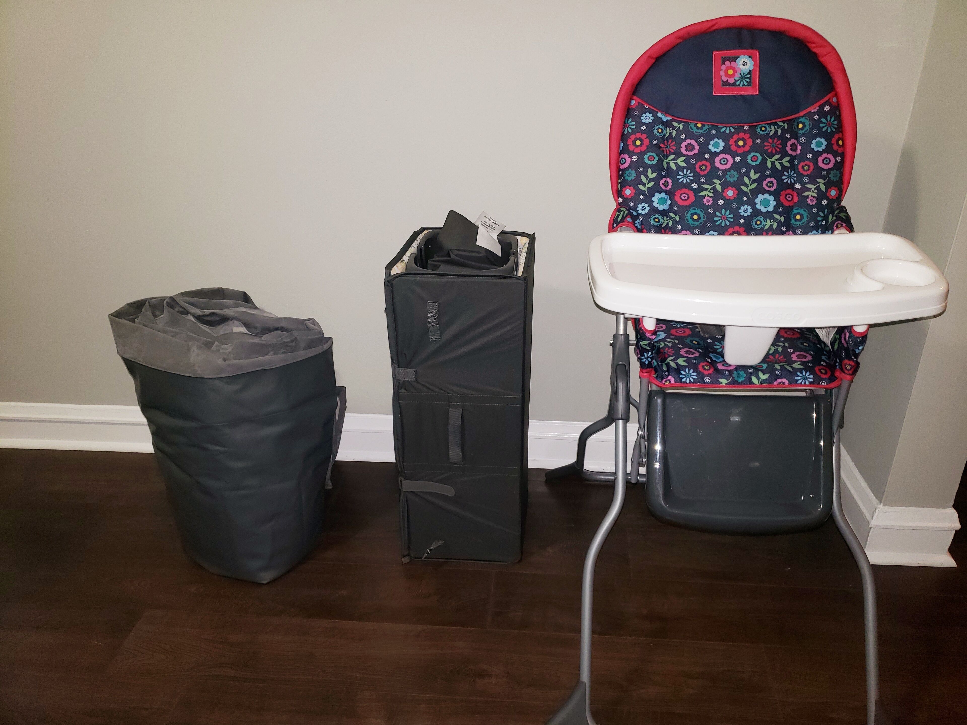 Una habitación con un cubo de basura, un baúl y un cochecito de bebé.