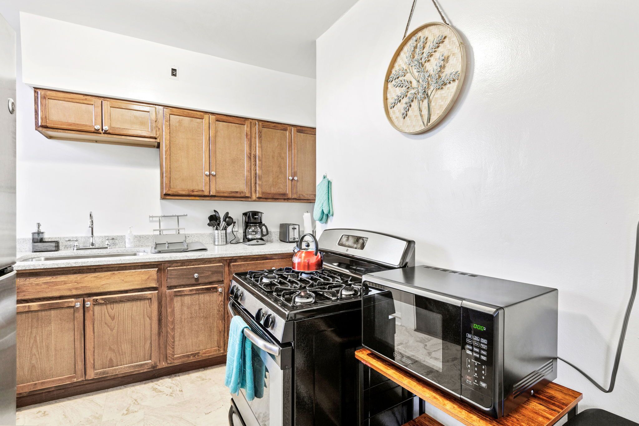 A kitchen with wooden cabinets, a gas stove, a microwave, and a coffee maker.
