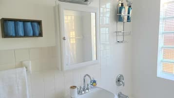 A bathroom with a white sink, a mirror, and a shower area.