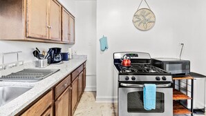 Una cucina compatta con mobili in legno, un fornello a gas, un forno a microonde e un piccolo piano di lavoro.