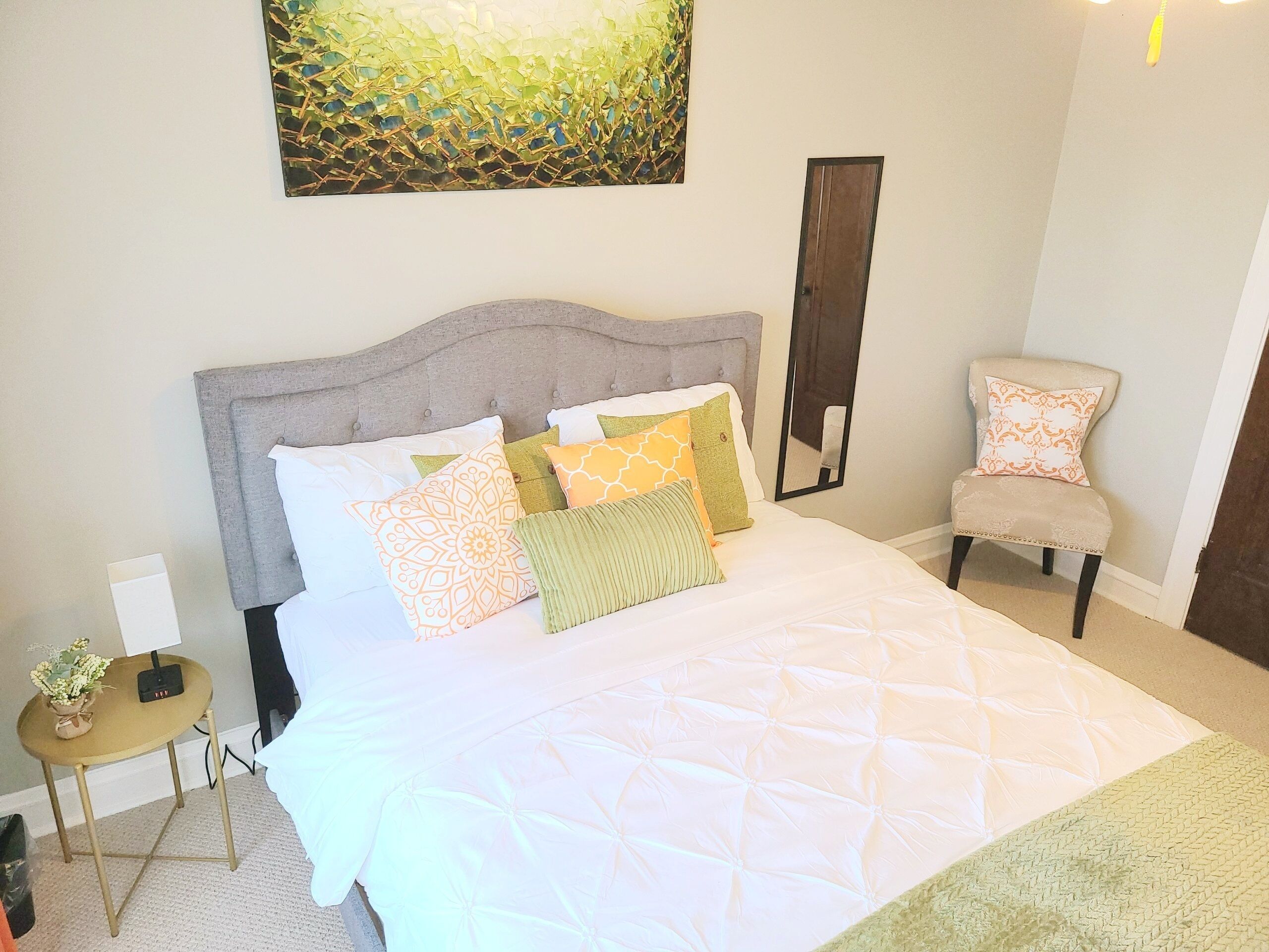 A neatly made bed with a quilted white duvet and several patterned pillows.