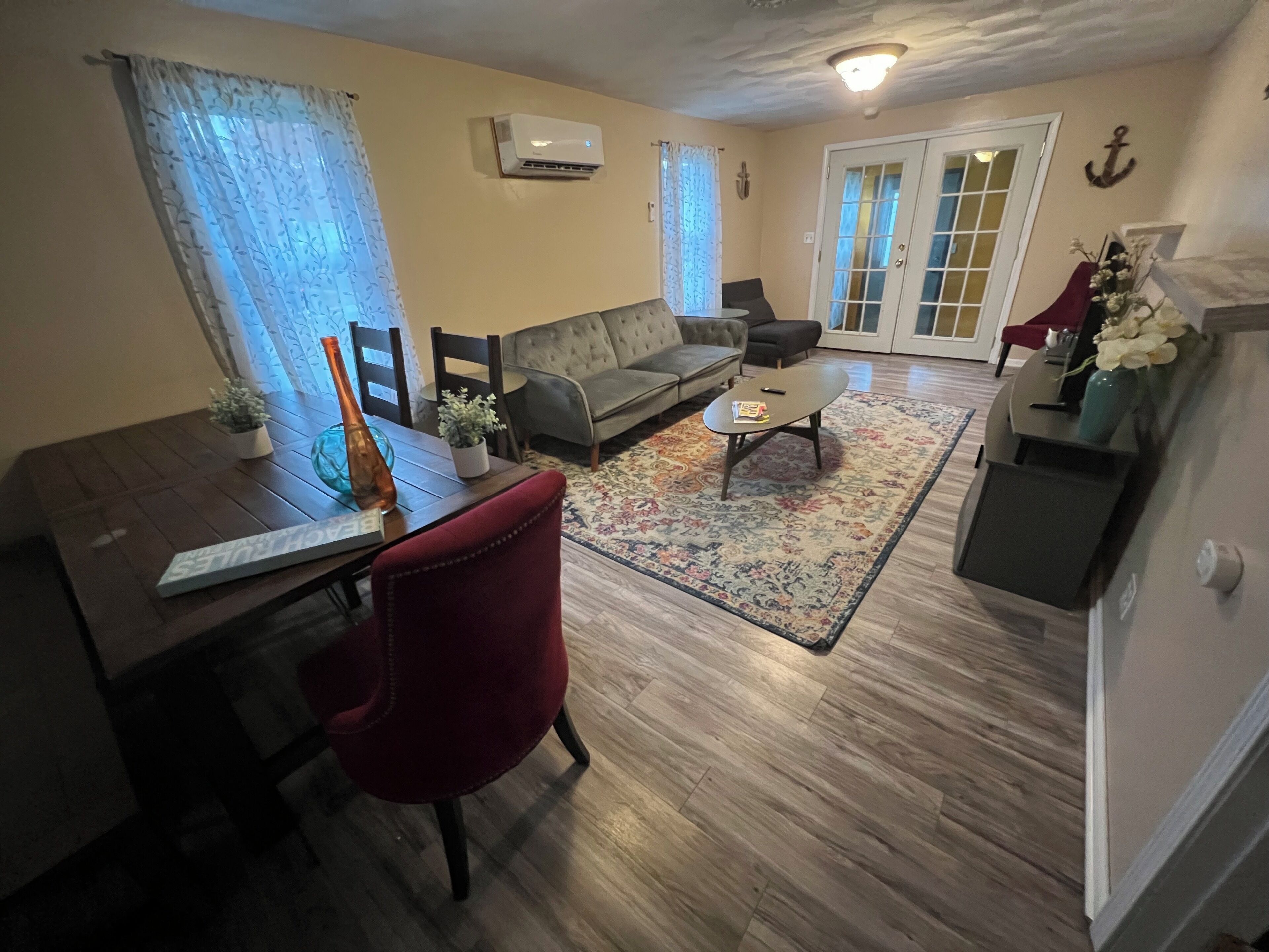 A living room with a sofa, a coffee table, a dining table with chairs, and a fireplace.