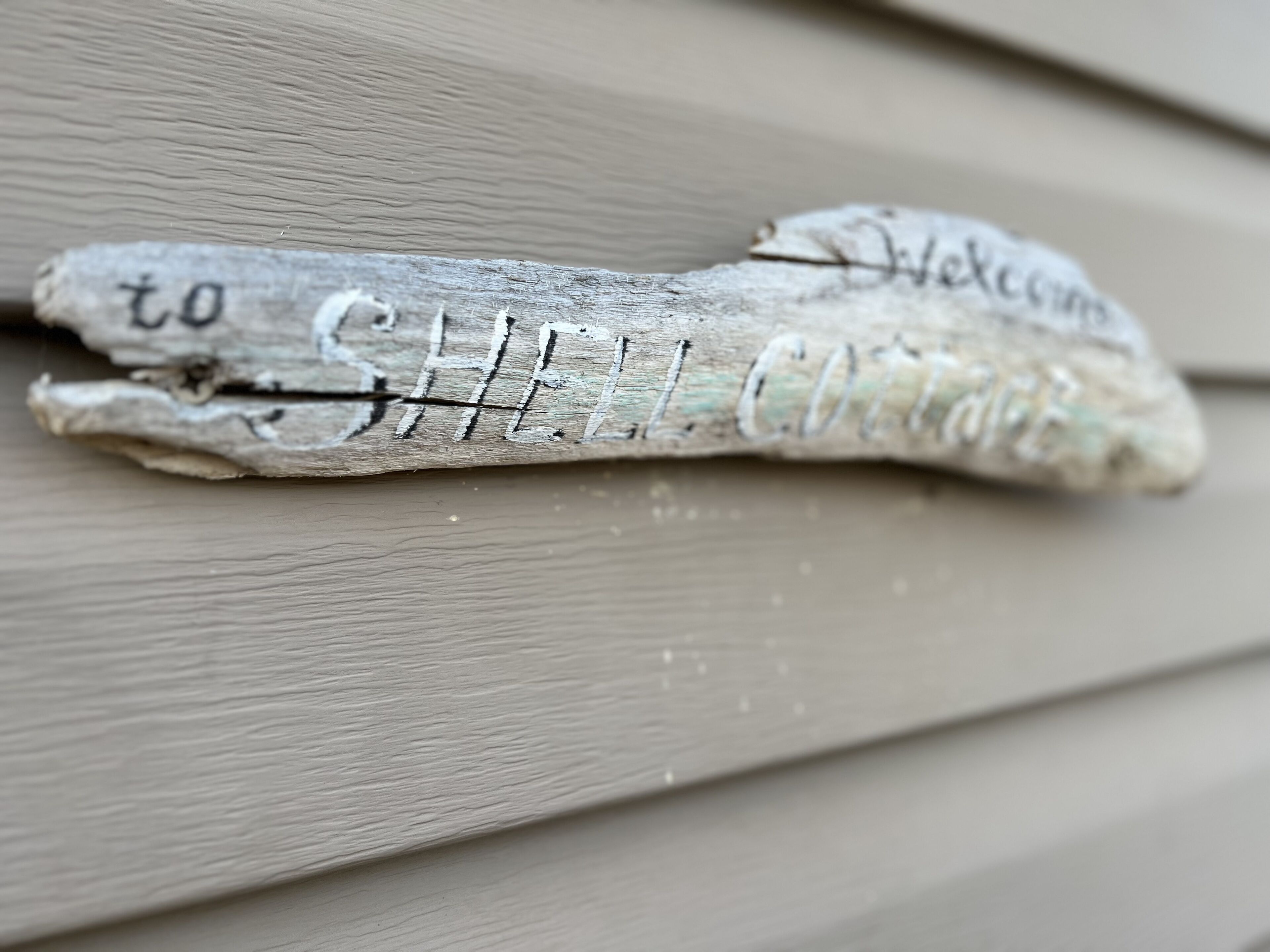 A wooden sign with the text "to SHELL COTTER" and "Welcome".