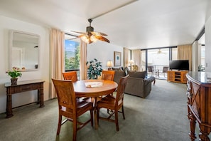 Ein geräumiges Wohnzimmer mit Essbereich, einem großen Flachbildfernseher und einem Balkon mit Blick.