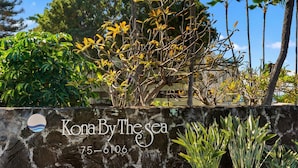 Eine Steinsäule mit dem Schriftzug "Kona By The Sea" und einer Telefonnummer.