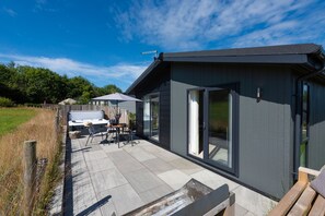 Ein modernes Haus mit Terrasse, Whirlpool und überdachter Sitzgruppe.