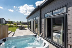 A modern house with a large patio, a hot tub, and a view of the neighborhood. - Primrose Lodge, 25 Roadford Lake Lodges (Lifton)