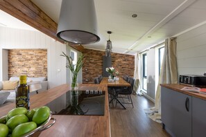 Cozinha moderna com bancadas de madeira, fogão embutido e área de refeições com mesa e cadeiras de madeira.