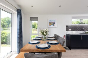 A modern kitchen with dark cabinetry, a marble countertop, and a dining area with a wooden table set for four.