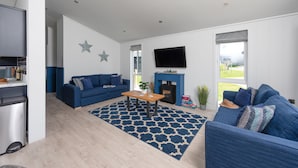 Een moderne woonkamer met een blauwe bank, een houten salontafel en een open haard.
