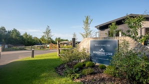 Welkomstbord voor Roadford Lake Lodges, met een stenen muur en een houten poort.