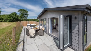 A modern house with a patio area featuring outdoor furniture and a hot tub.