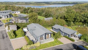 A residential area with modern houses, a swimming pool, and a view of a lake. - Orchid Lodge, 23 Roadford Lake Lodges (Lifton)