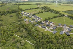 An aerial view of a residential area with modern houses, a road, and a wind turbine.