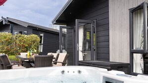 Un jacuzzi frente a una casa con una mesa y sillas en el patio.