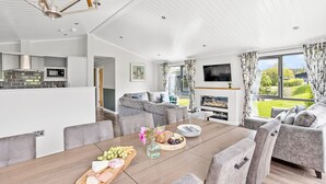 Una sala de estar moderna con comedor, cocina y chimenea.