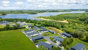 Zona residencial con casas modernas, un lago y abundante vegetación.