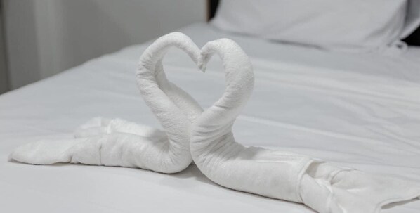 Una cama con una toalla dispuesta en forma de corazón.