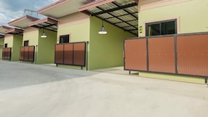 A row of hotel rooms with a green facade, large windows, and a concrete floor. - Get Sleep (Tha Sala)