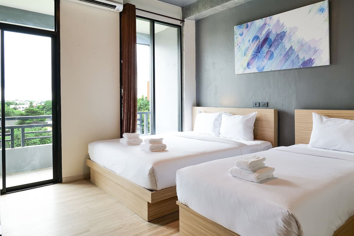 Quarto de hotel moderno com duas camas, uma janela grande com cortinas, um quadro na parede e vista para a varanda.
