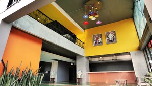 A multi-level interior with a yellow and orange color scheme, a staircase with black railings, and two framed pictures on the wall. - B2 Chiang Rai Phahonyothin Boutique & Budget Hotel (Chiang Rai)