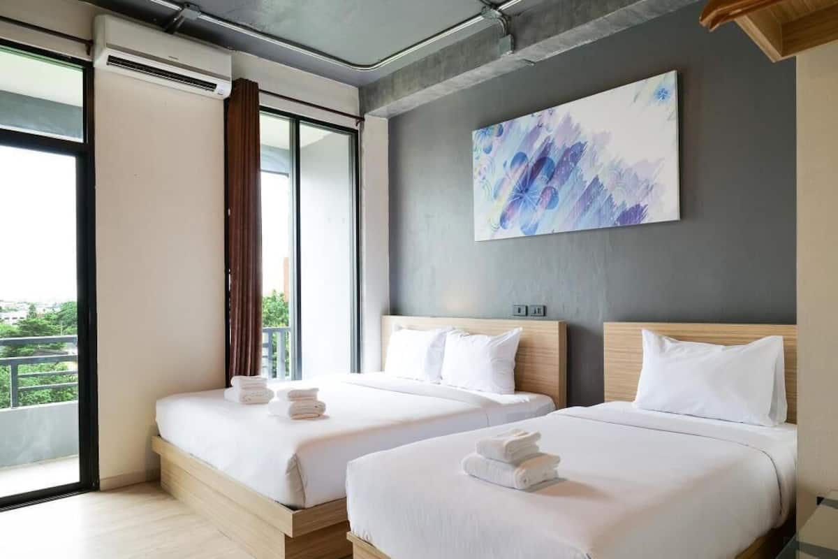 Quarto de hotel com duas camas, uma janela grande e um quadro na parede.