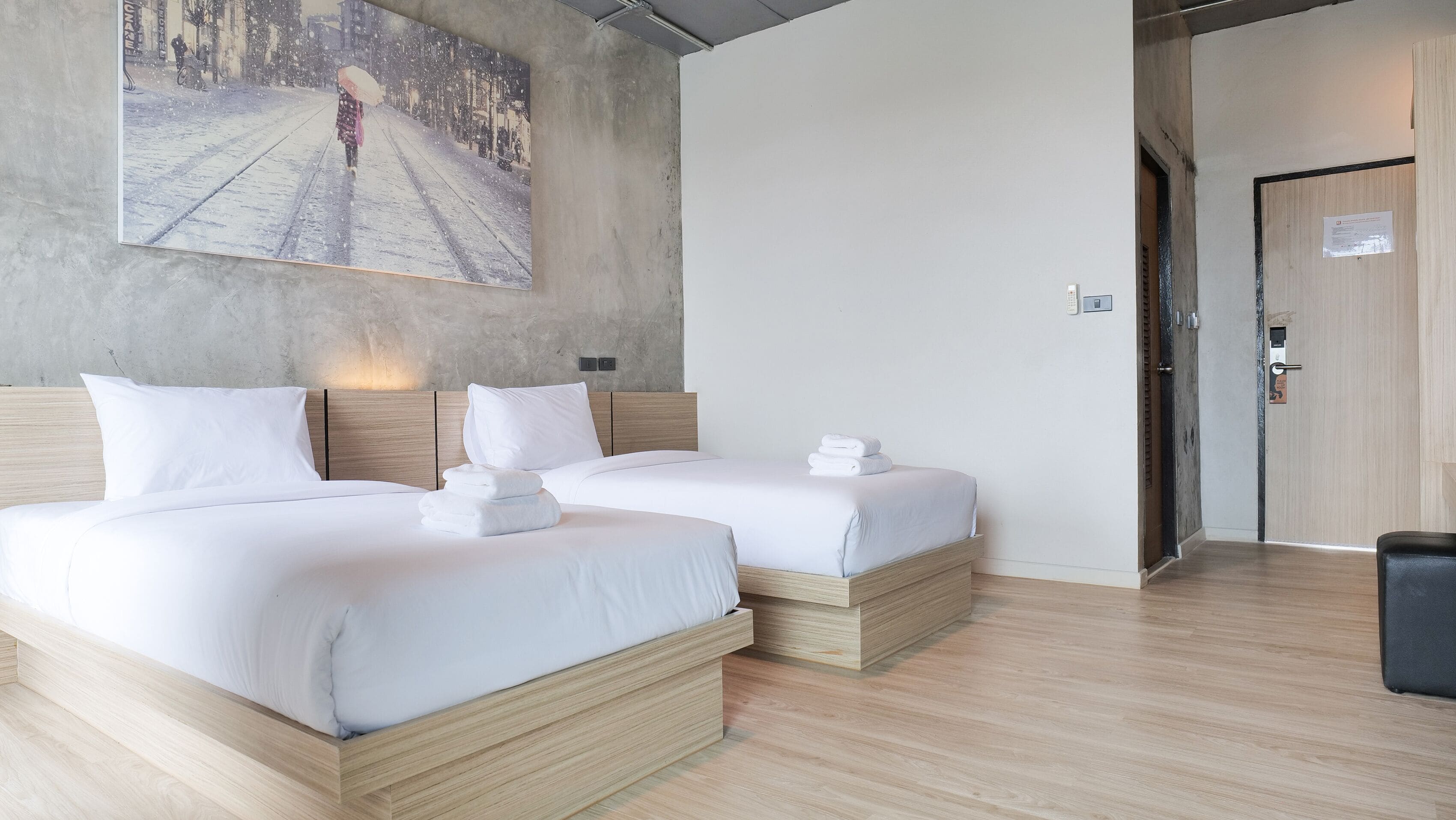 Ein Hotelzimmer mit zwei Betten, einem großen Gemälde an der Wand und Holzboden.