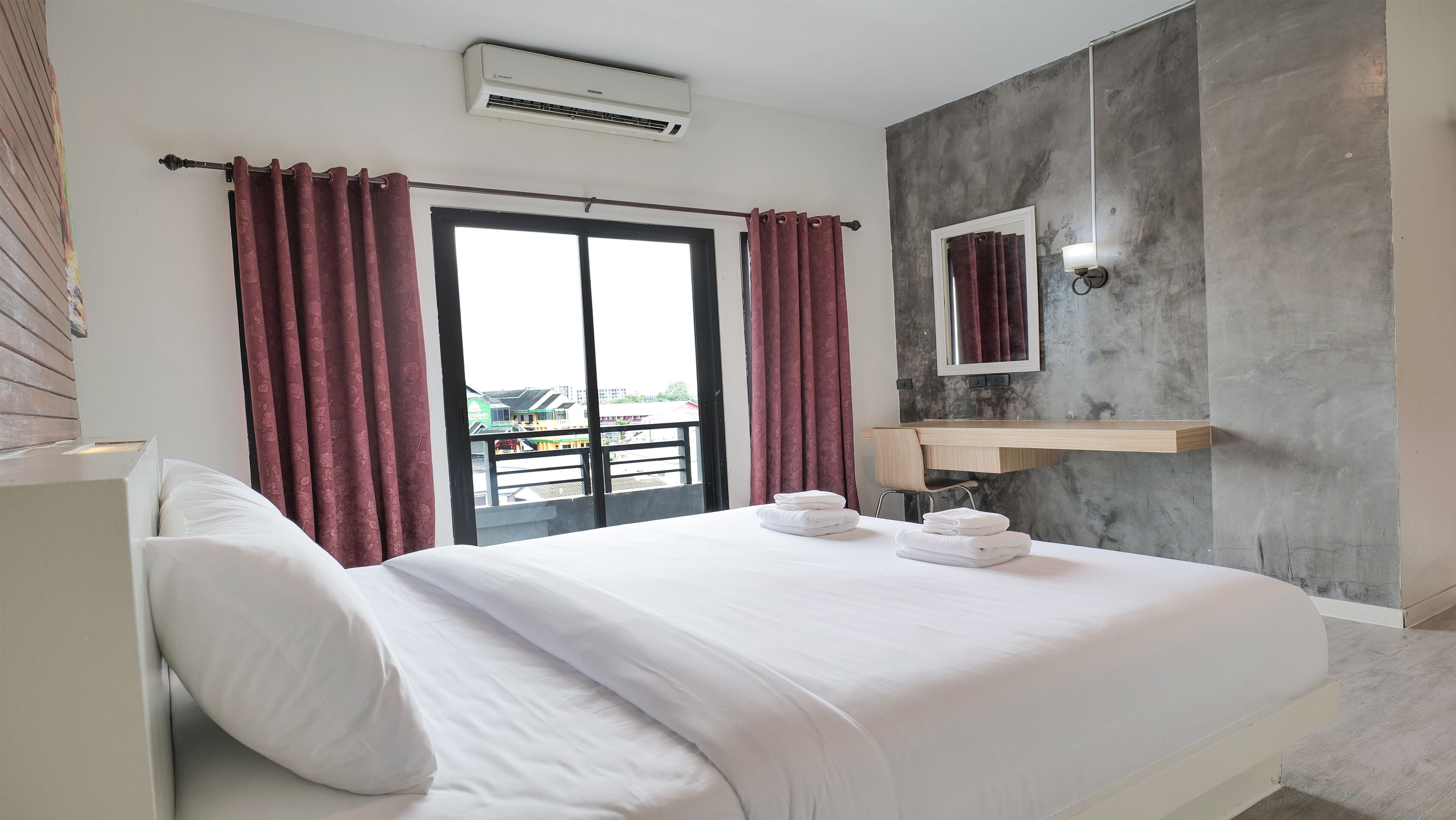 Habitación de hotel con cama, baño con espejo y perchero, y balcón con vistas.