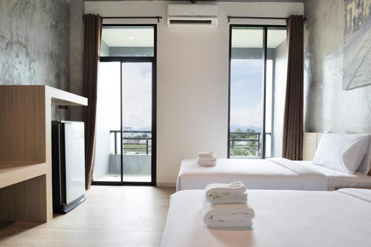 Quarto de hotel com duas camas, uma mesa de trabalho e vista para a cidade.