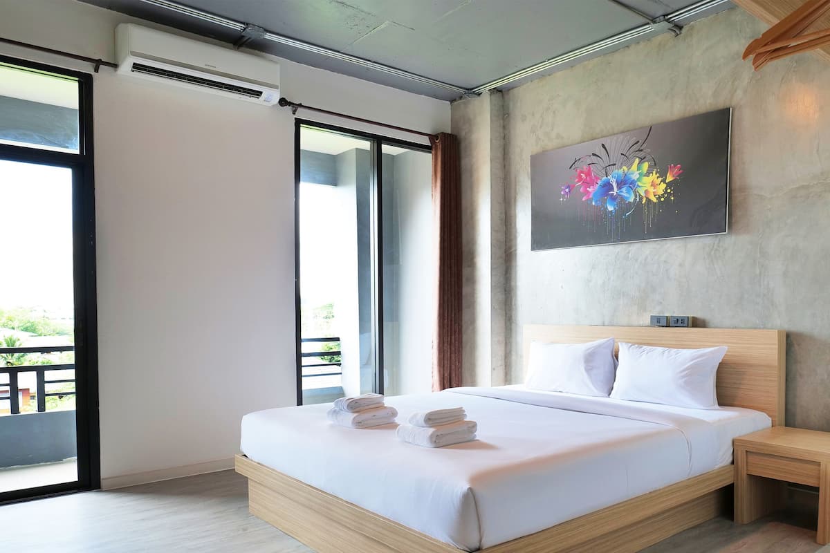 Quarto moderno com cama grande, cabeceira de madeira, mesa de cabeceira e um quadro na parede.