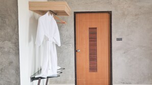 A bathroom with a wooden door, a towel rack with a white towel, and a glass shower area. - B2 Chiang Rai Phahonyothin Boutique & Budget Hotel (Chiang Rai)