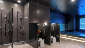 A modern shower area with multiple showerheads and a seating area with bottles. - Cross Life Hakata Tenjin （ORIX HOTELS & RESORTS） (Fukuoka)
