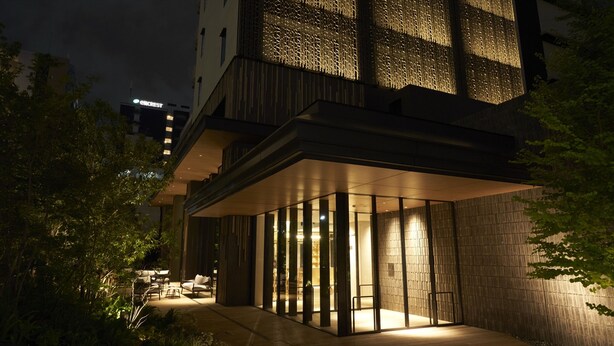 A modern building with a glass facade, outdoor seating area, and a visible sign for a nearby hotel. - Cross Life Hakata Tenjin （ORIX HOTELS & RESORTS） (Fukuoka)